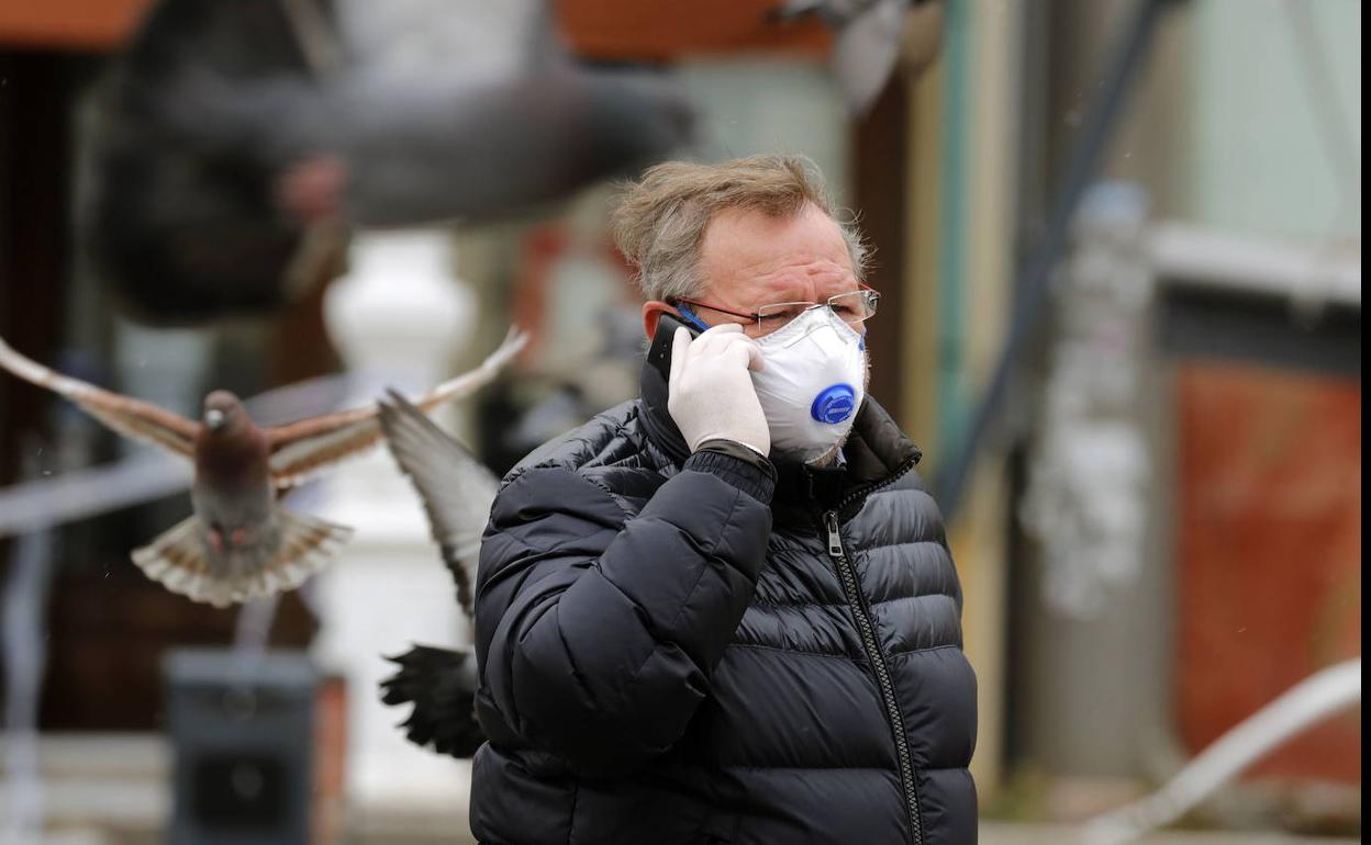 Un hombre con mascarilla habla por el móvil.