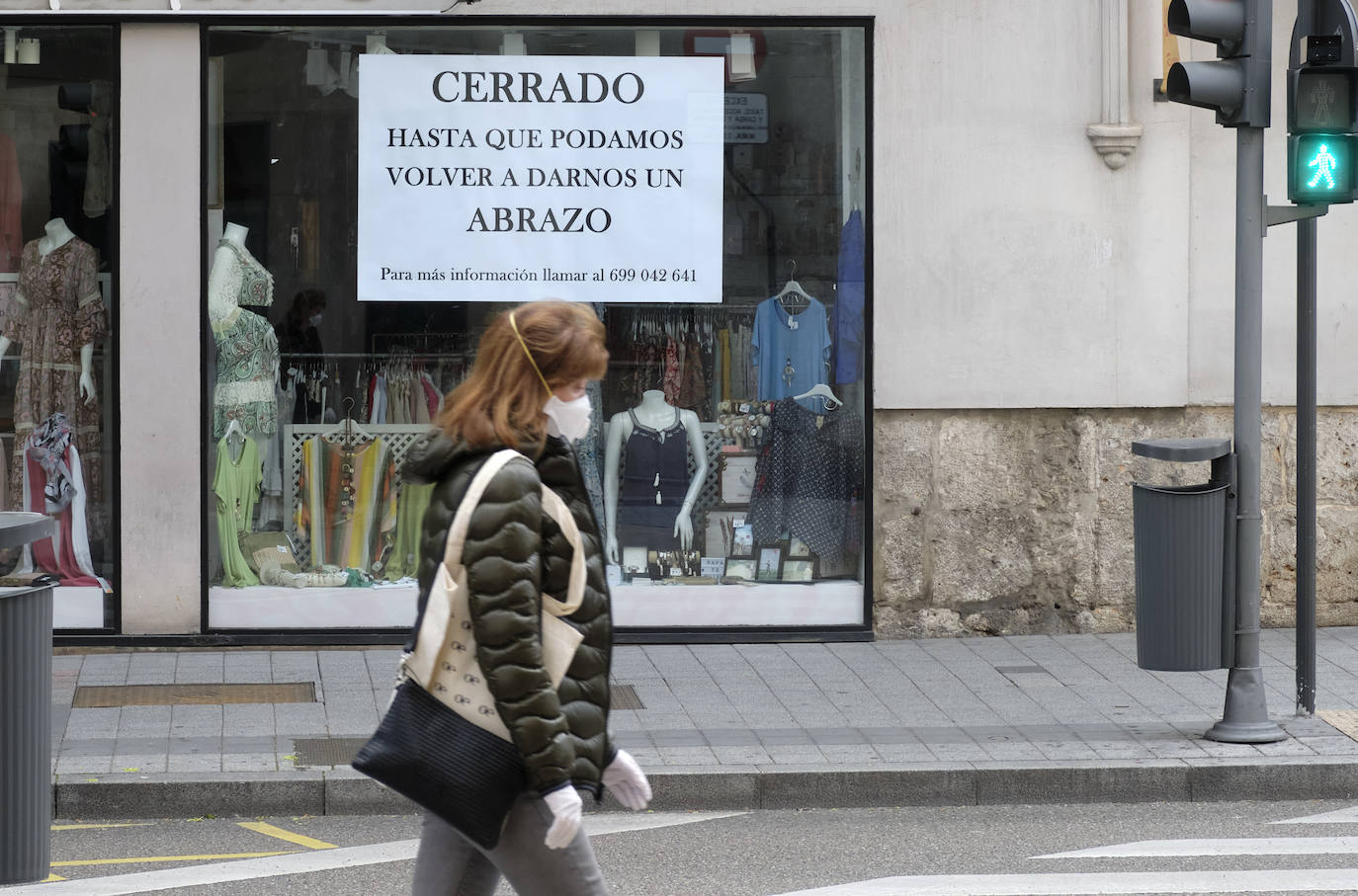 Una mujer pasa frente a un comercio cerrado en Valladolid. 