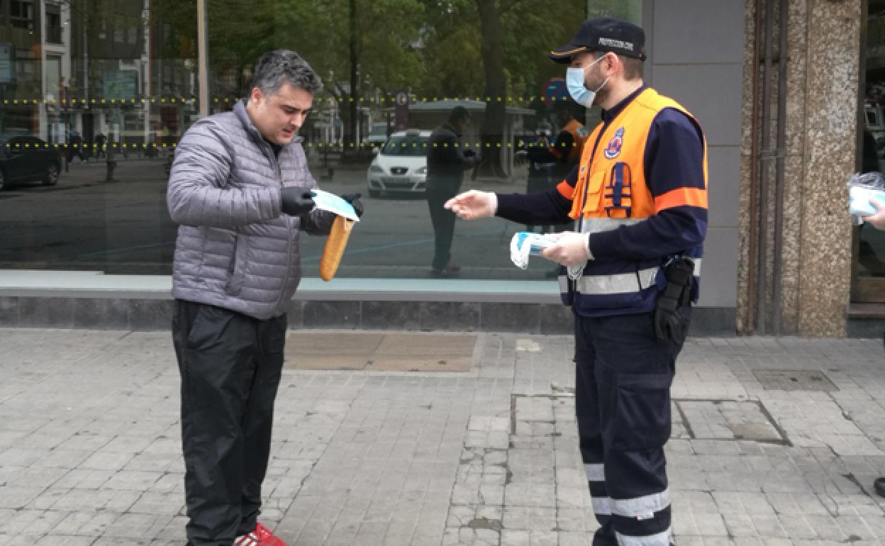 Un voluntario de Protección Civil entrega una mascarilla a un ciudadano. 