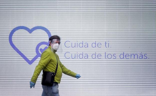 Un hombre camina con mascarilla, guantes y pantalla protectora por una calle del centro de A Coruña. 