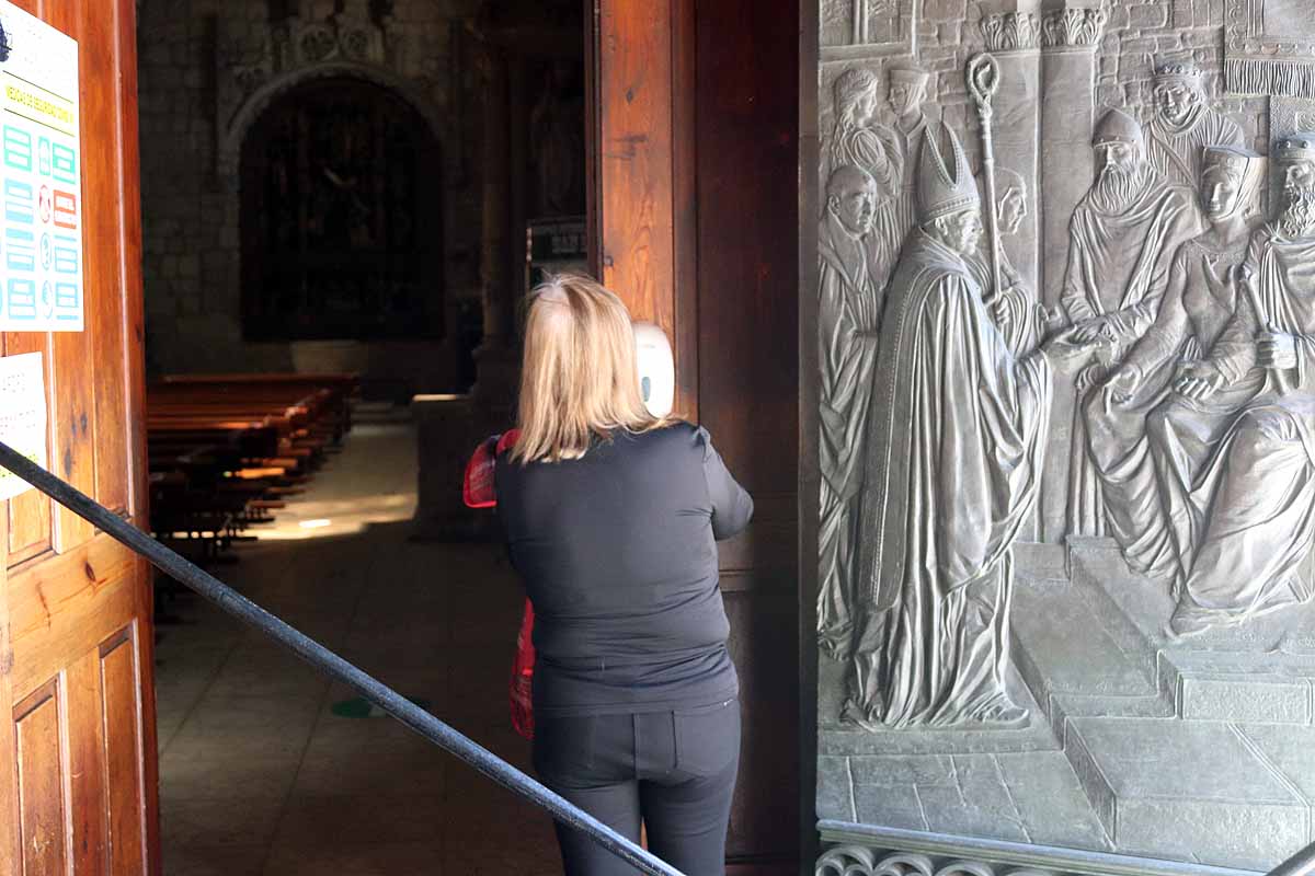 Una mujer se echa gel desinfectante a la entrada de la iglesia deSan Lesmes en Burgos. 