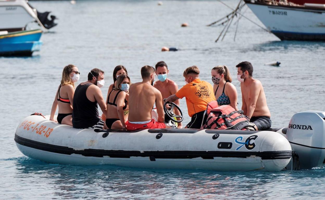 Participantes de actividades acuáticas con mascarilla en una zodiac por aguas de Gran Canaria. 