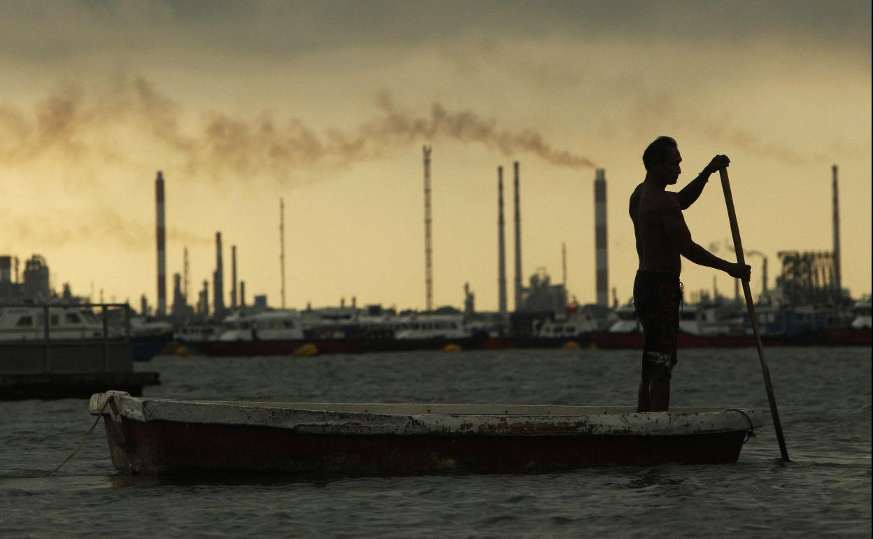 Un pescador avanza con su bote cerca de una refinería de petróleo, cerca de las terminales portuarias en Singapur. 