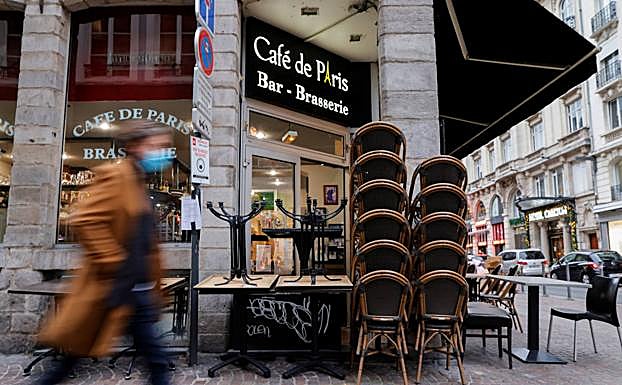 Sillas y mesas apiladas en el exterior de una cafetería en Lille.