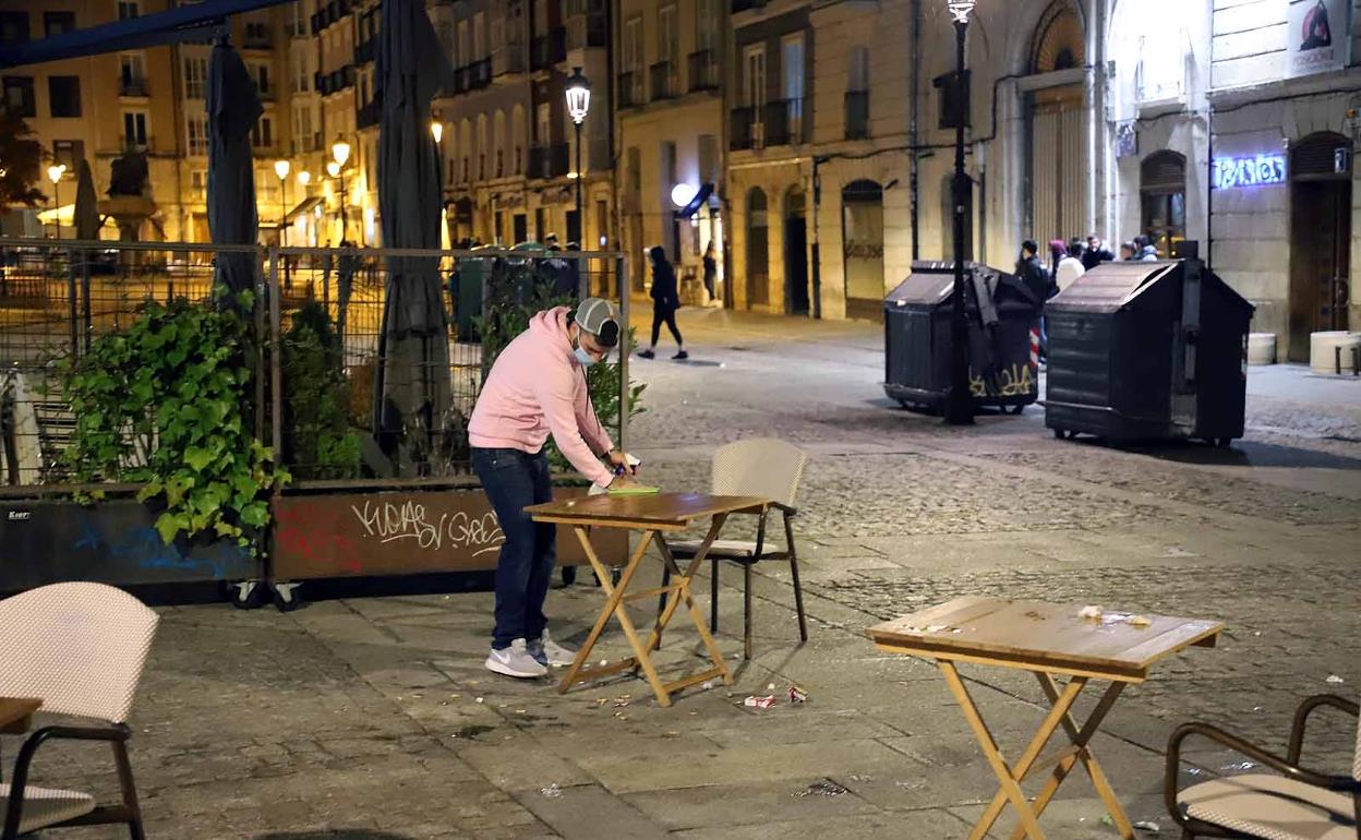 Un hostelero recoge la terraza el último día que se abrió la hostelería.