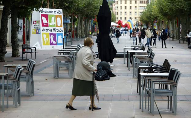 Una señora pasa ante una terraza vacía en Miranda de Ebro.