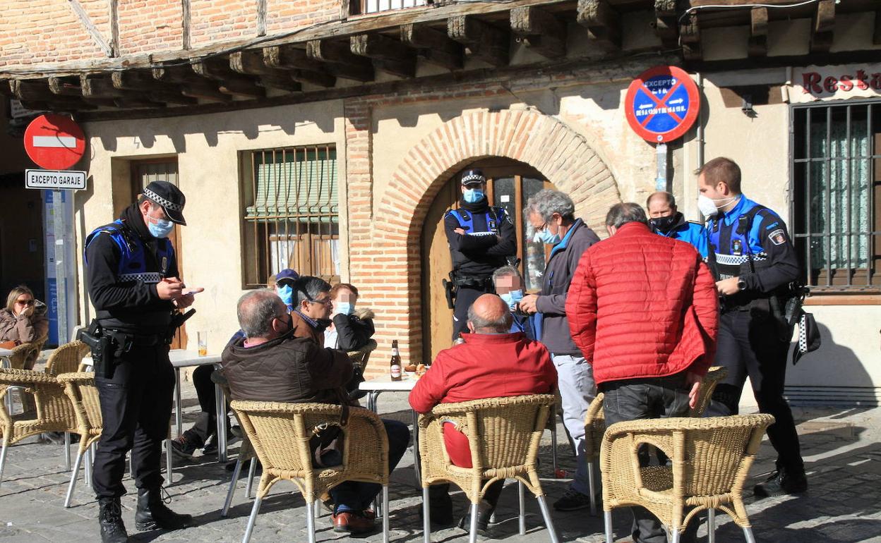 La policía local efectúa identificaciones a clientes sentados en la terraza de un bar.