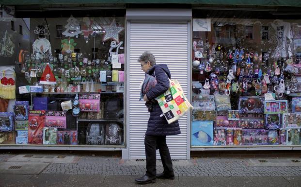 Una mujer pasa por delante de una tienda cerrada por las restricciones.