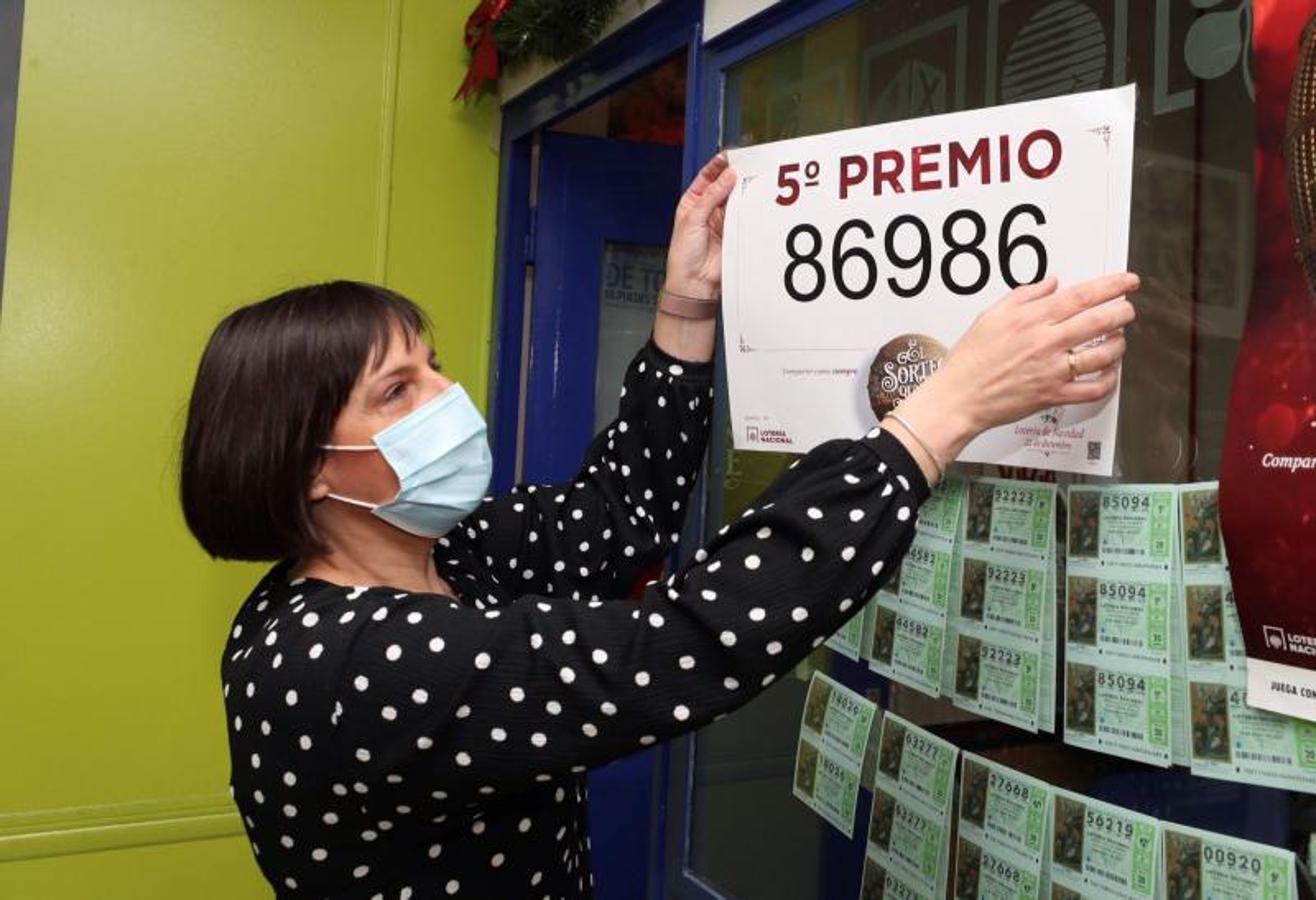 La propietaria de la administración de lotería 81 de Zaragoza coloca el cartel tras haber vendido décimos del número 86986.