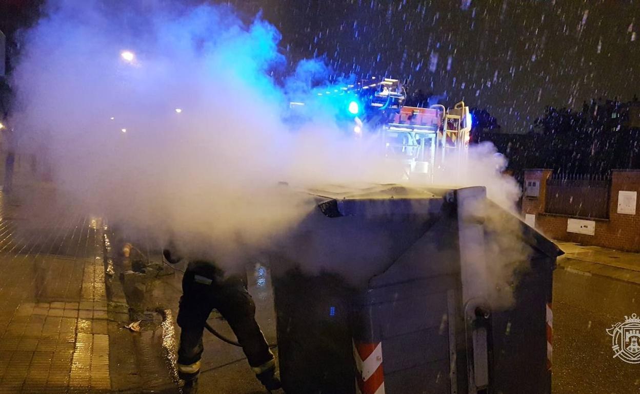 Los Bomberos extinguen las llamas de un contenedor quemado.