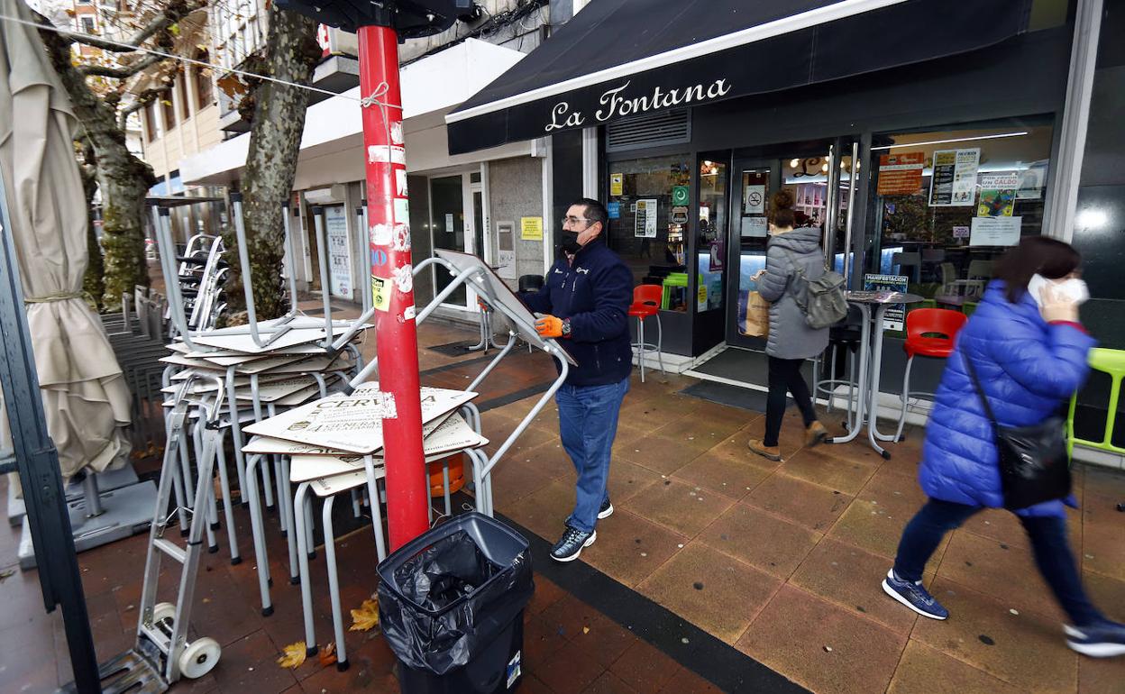 Un hombre recoge la terraza de un bar.