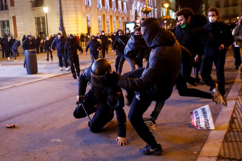 Varios manifestantes apalean a un policía en la Puerta del Sol de Madrid.