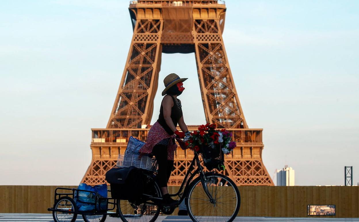 Una ciclista pasa ante la torre Eiffel de París.