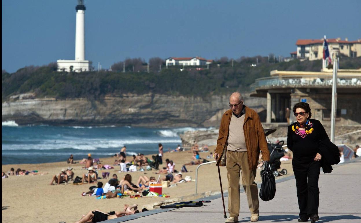 Una pareja de jubilados pasea junto a una playa. 
