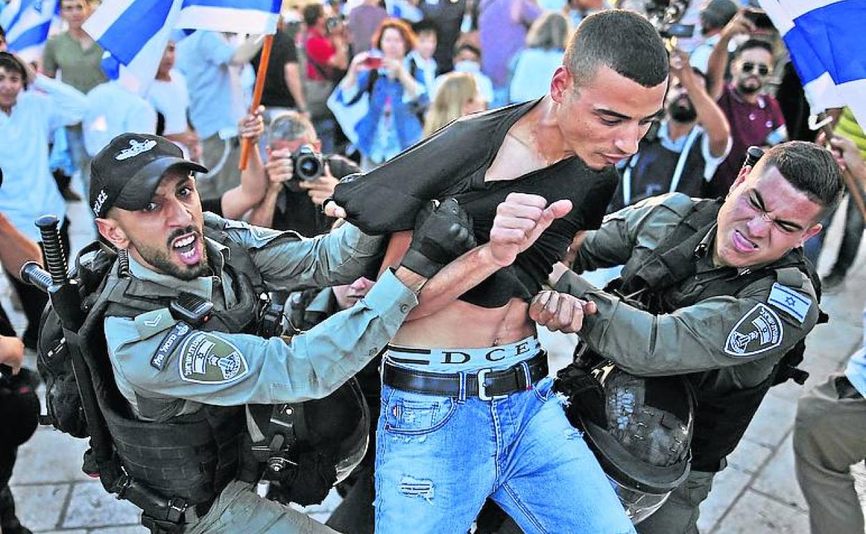 Dos agentes arrestan a un palestino en medio de la marcha de ultranacionalistas judíos en Jerusalén.