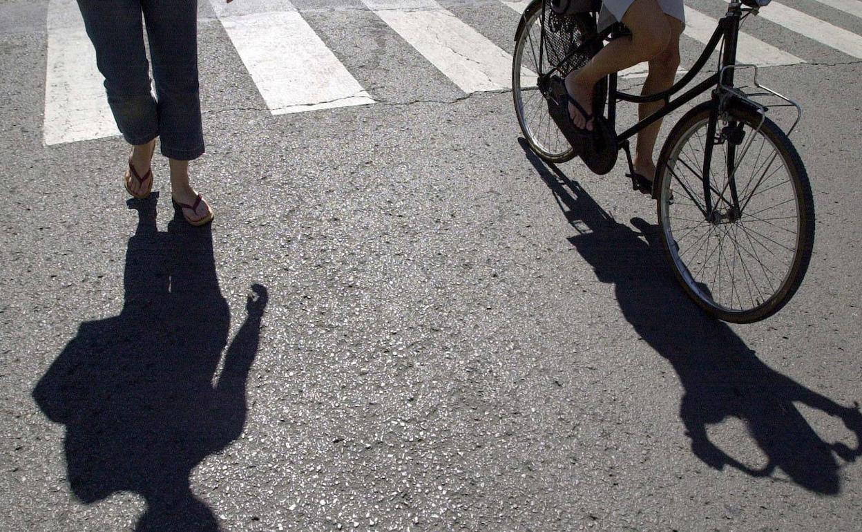 Un peaton y un ciclista pasean por una carretera vacia. 