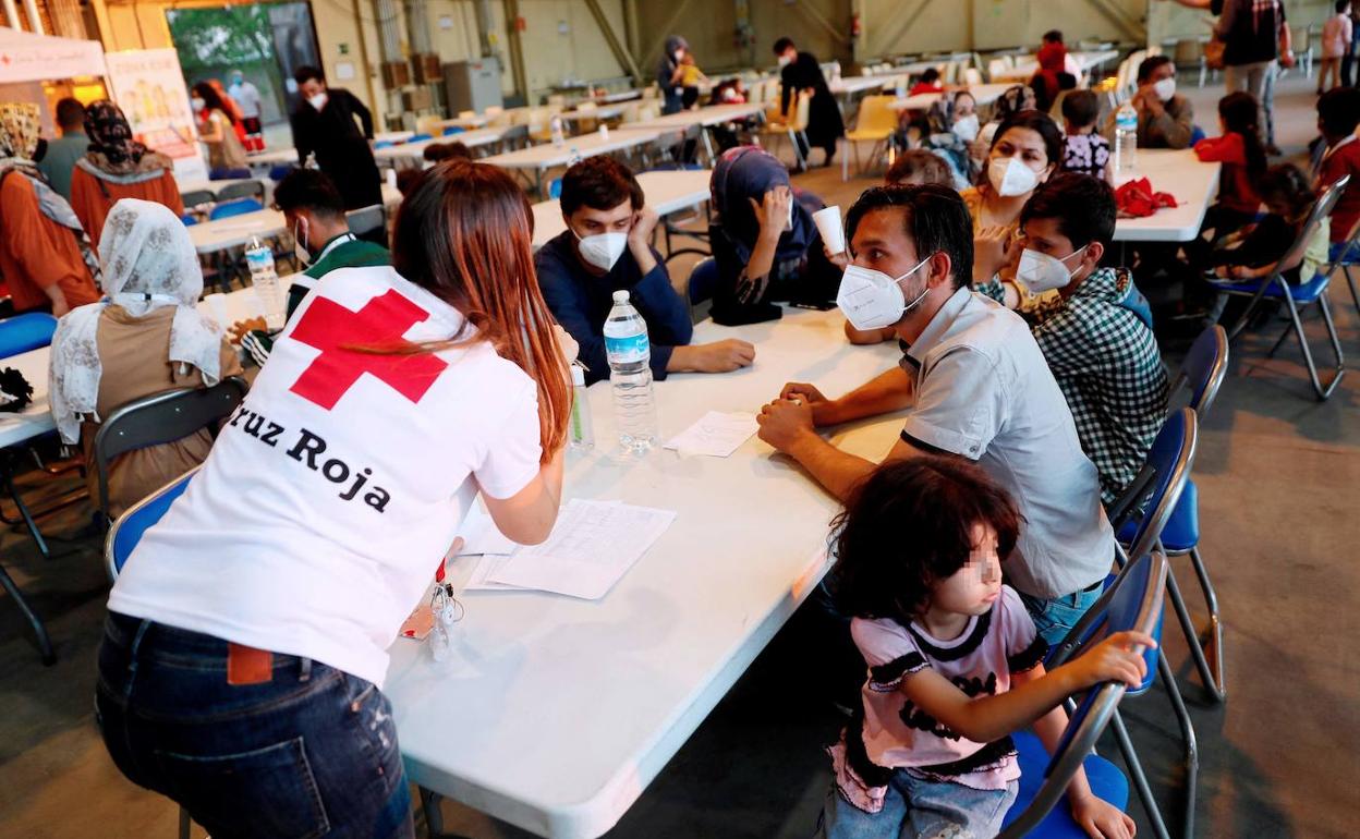 Una voluntaria de Cruz Roja conversa con una familia afgana en el centro provisional creado en Torrejón de Ardoz.