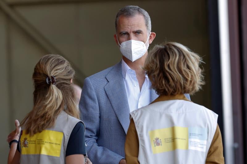 El rey Felipe VI conversa con dos personas durante su visita este sábado al centro de acogida temporal instalado en la base de Torrejón.