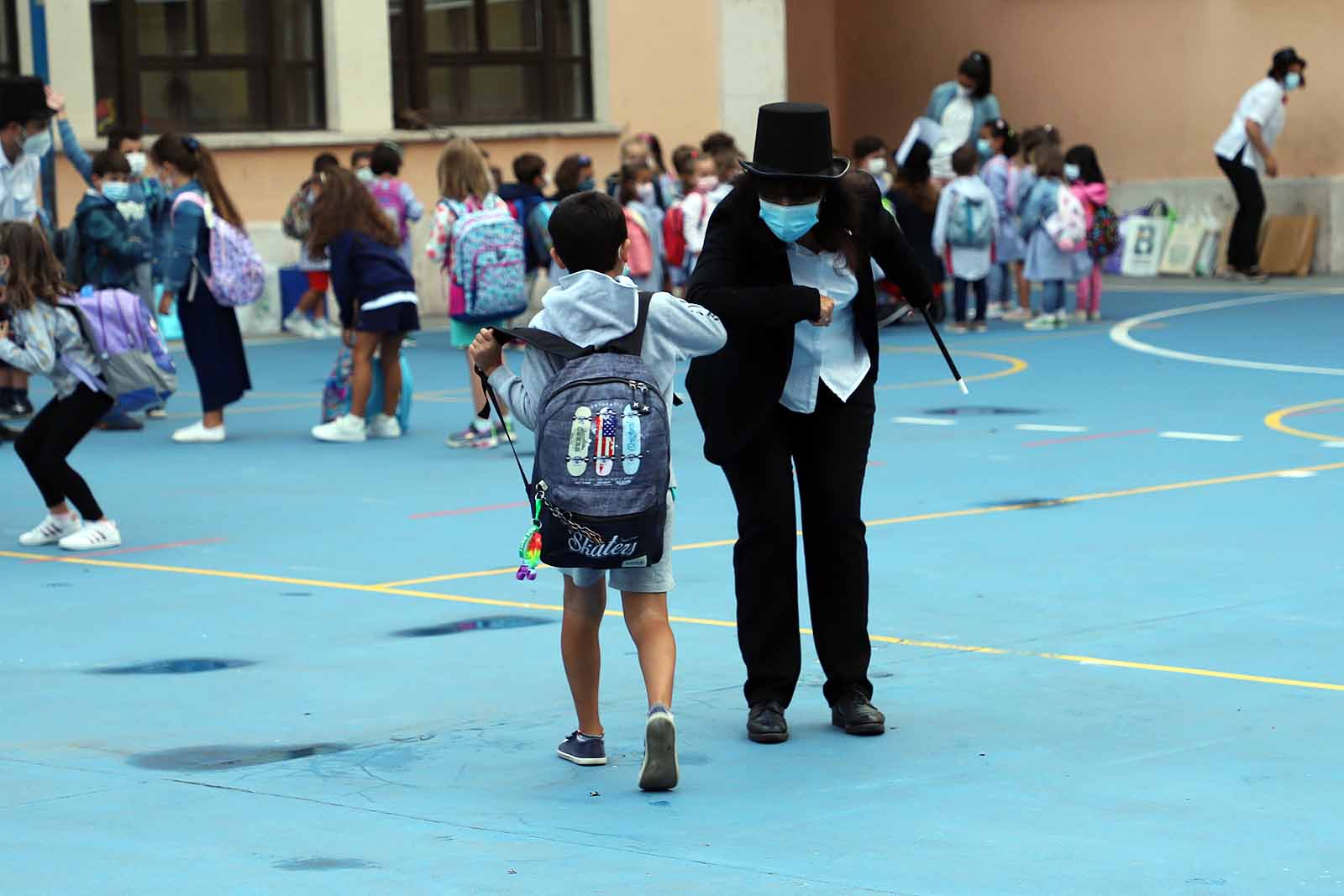 Una profesora saluda con el cole a uno de sus alumnos.