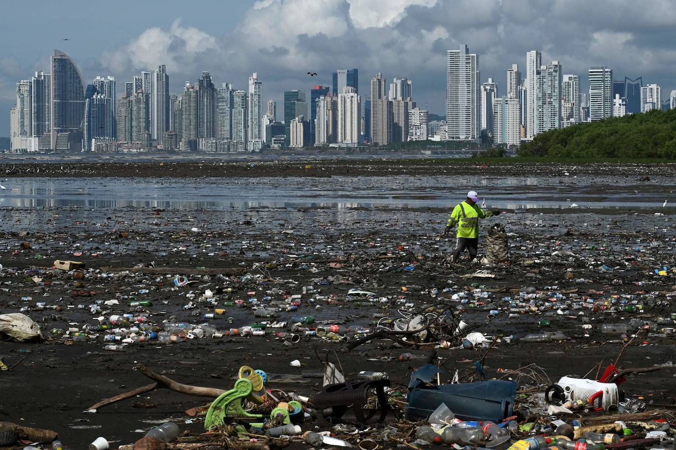 Un hombre recolecta basura, incluidos desechos plásticos, en la playa de Costa del Este, en la Ciudad de Panamá, el 19 de abril de 2021