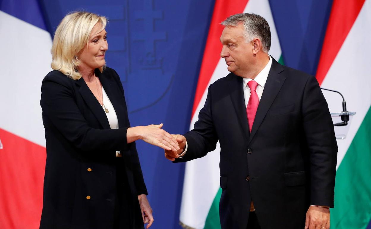 Marine Le Pen se dispone a estrechar la mano de Viktor Orban durante su encuentro.