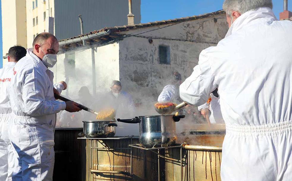 Los cofrades de la Cofradía de San Antón se encargan de repartir las raciones de titos. 