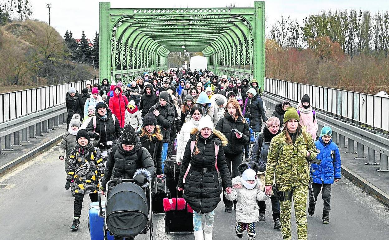 Cientos de refugiados cruzan el puente que separa la frontera de Ucrania con Polonia.