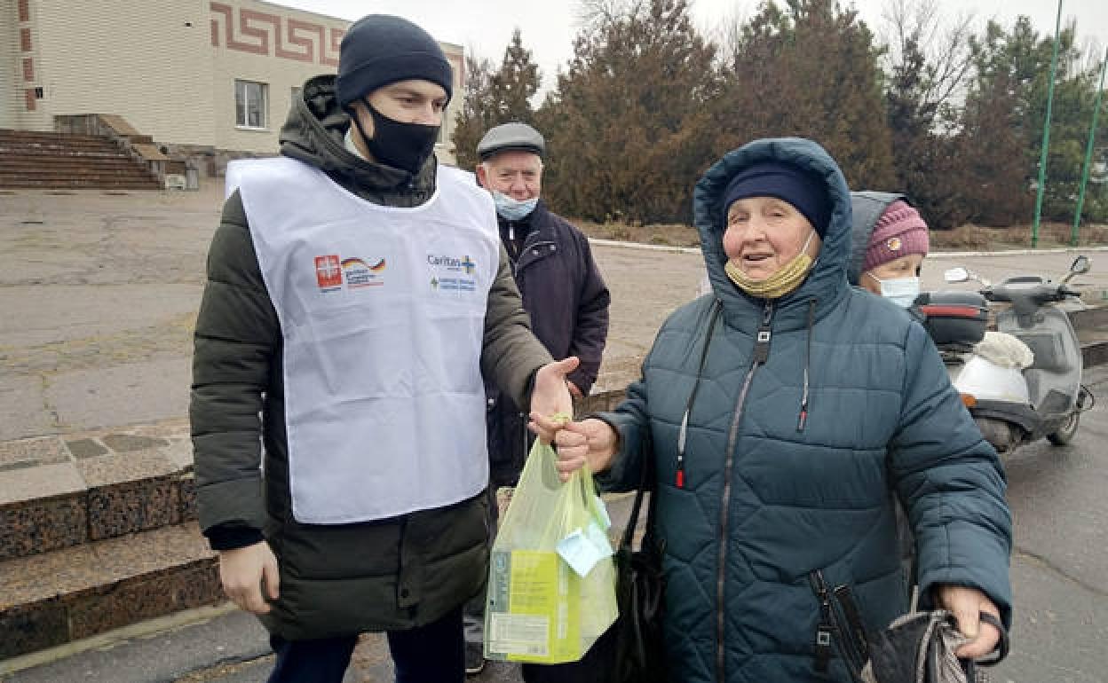 Un voluntario de Cáritas entrega alimentos a una mujer ucrania. 