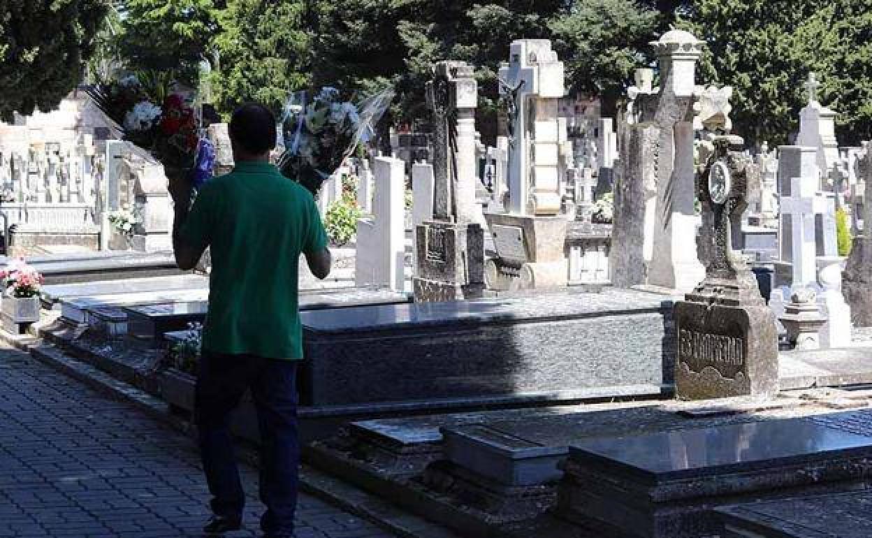 Un hombre lleva dos ramos de flores al cementerio de San José en Burgos. 