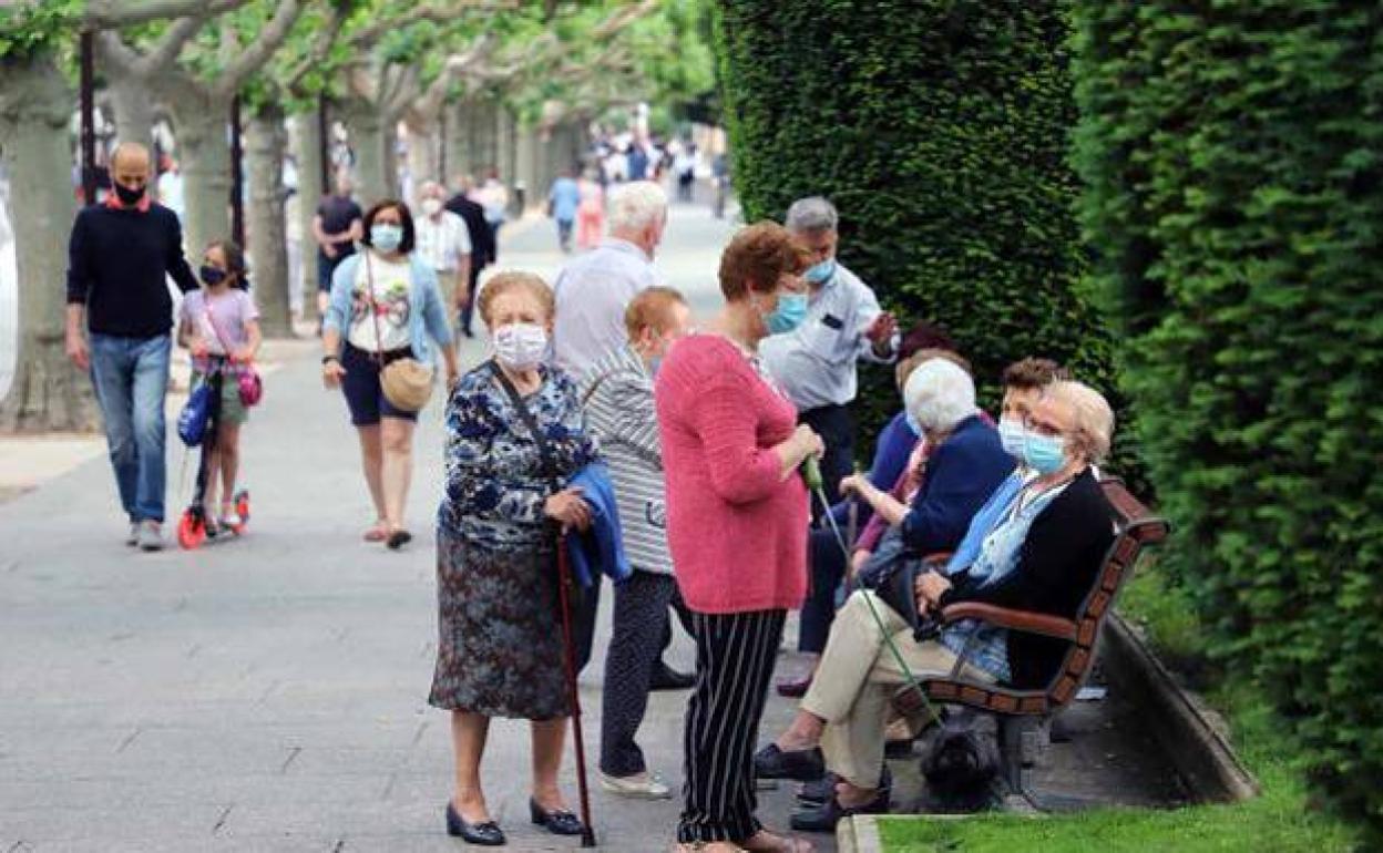 Personas mayores sentadas en uno de los bancos del Paseo del Espolón en Burgos