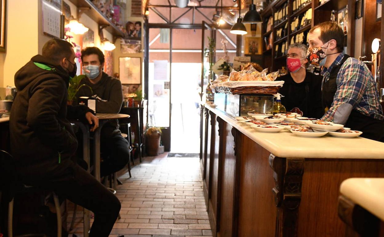 Clientes y hosteleros conversan tras la barra de un pequeño local