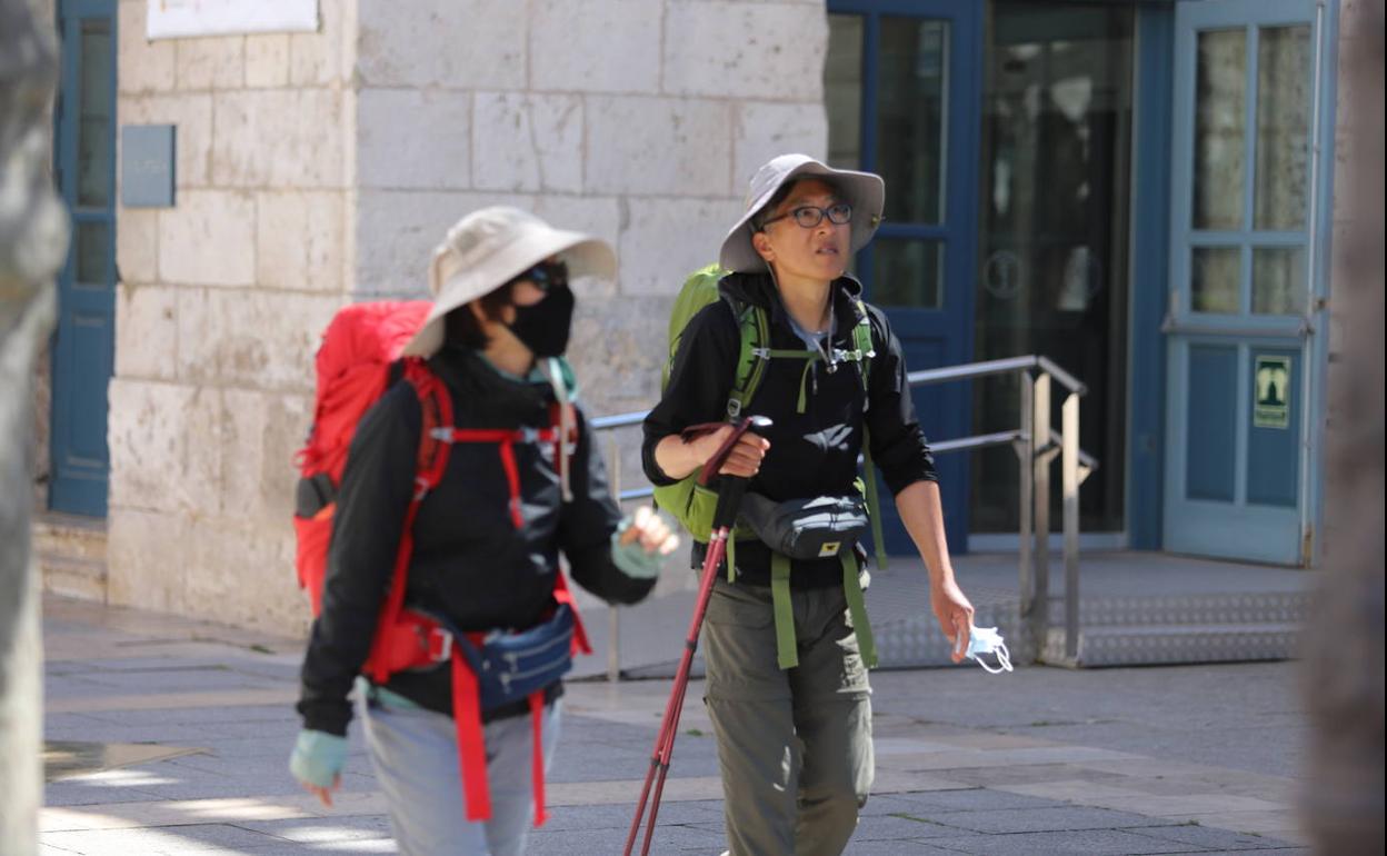 Dos peregrinos coreanos caminan por el Paseo del Espolón de la capital