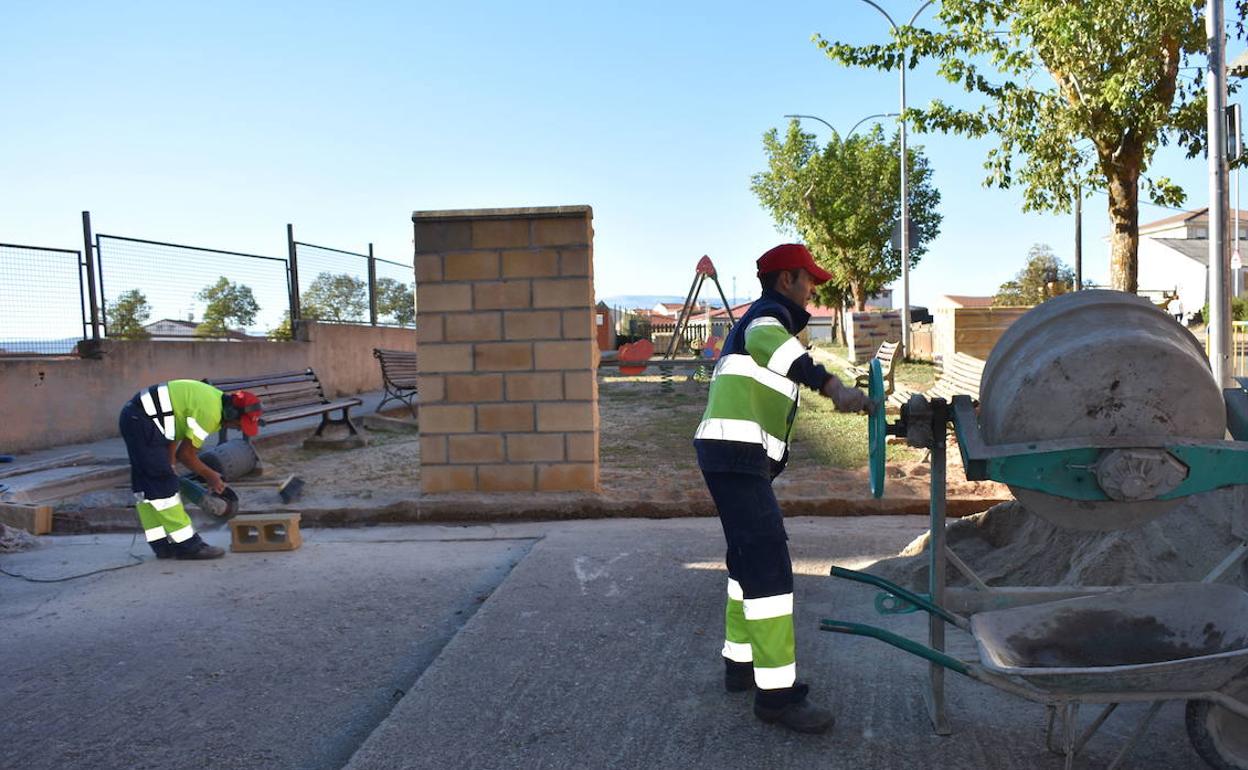 Imagen de archivo de dos empleados municipales trabajando en un parque. 