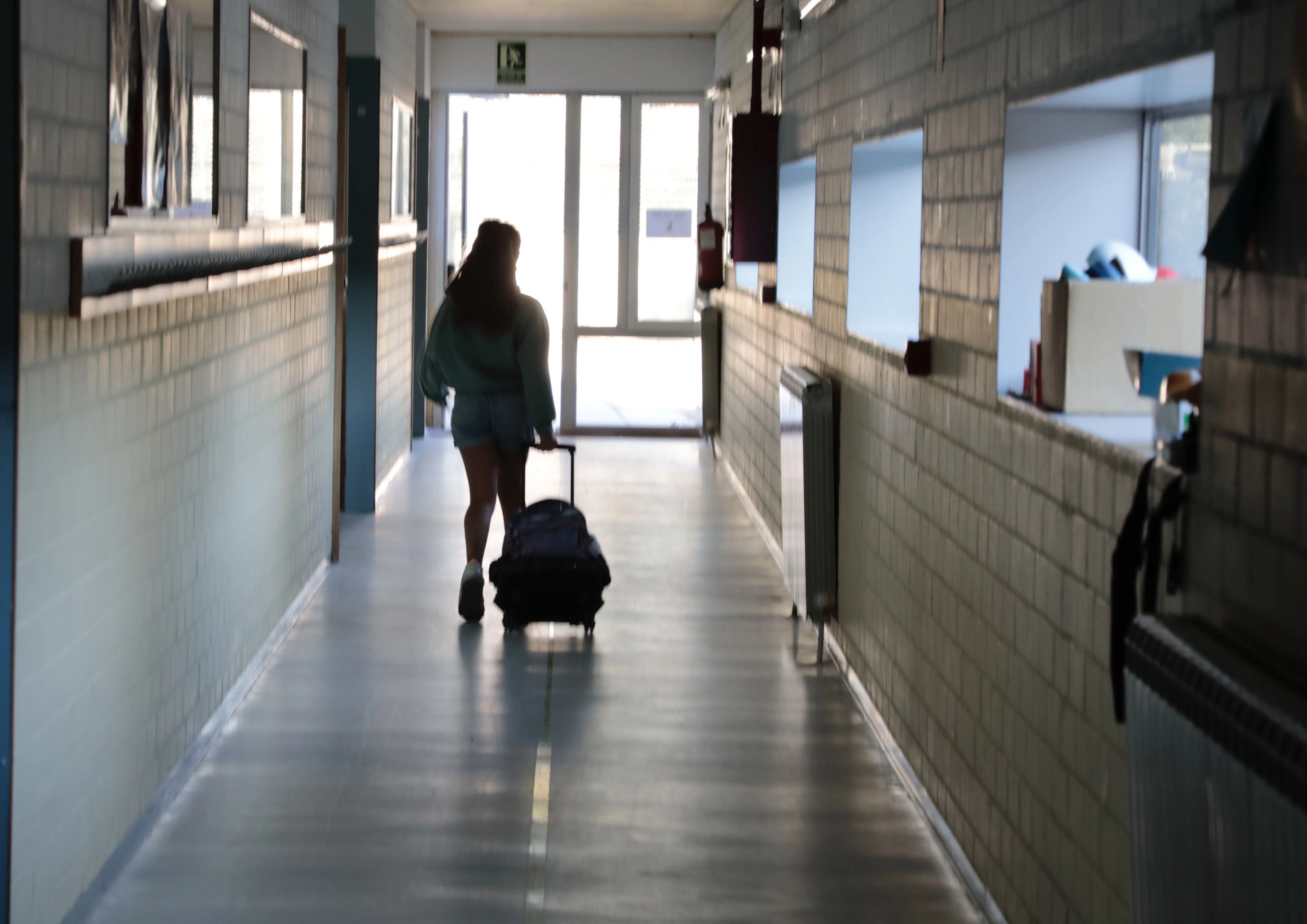 Una niña recorre el pasillo de un colegio.