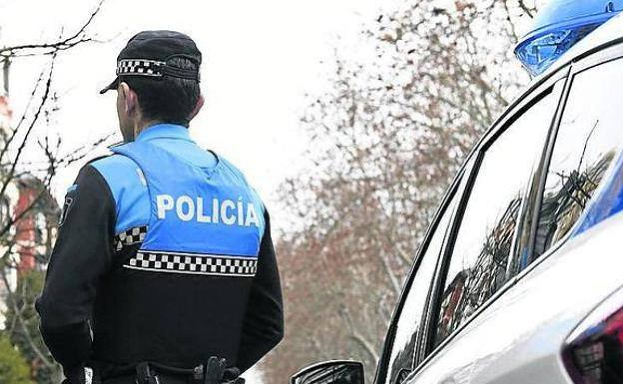 Imagen de archivo de un agente de Policia Local junto a un coche patrulla