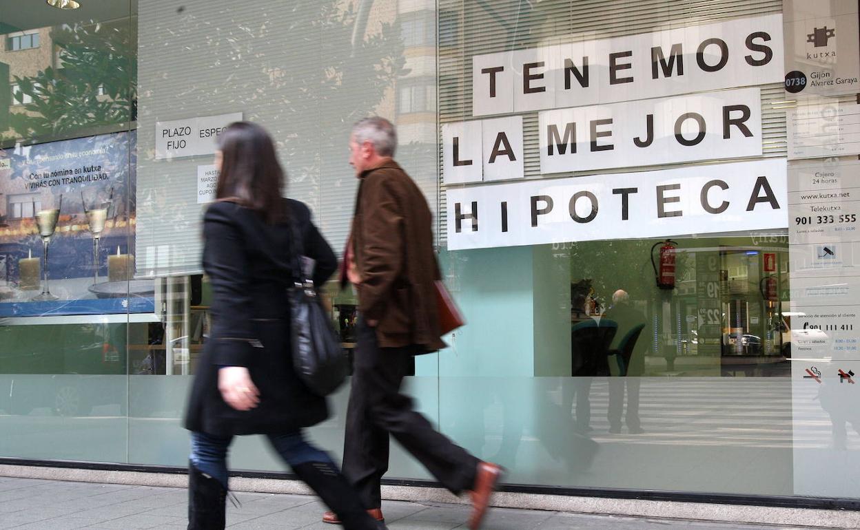 Viandantes ante el escaparate de una entidad financiera. 