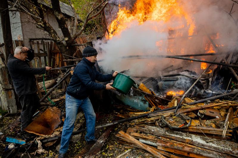 Dos vecinos de Bakhmut tratan de sofocar las llamas que devoran los restos de su casa bombardeada por los rusos