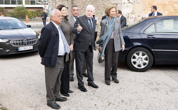 Imagen principal - Arriba, la Reina Doña Sofía a su llegada a Ibeas de Juarros; abajo, a la izq. Lls vicepresidentes de la Fundación y la doctora Rosa Huguet muestran el fósil de la parte de la cara del primer europeo a la reina; y a su dcha. los vicepresidentes entregan a la monarc varios libros.