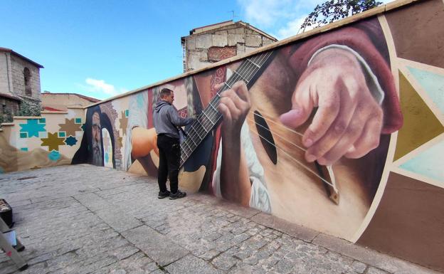 Galería. Cristian Fernández trabaja en las sombras del mastil de uno de los instrumentos que forman el mural del Callejón de la Brujas