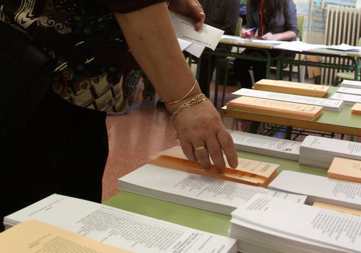 Una mujer escoge papeleta en un colegio electoral.