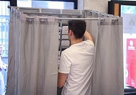 Un hombre coge las papeletas en su colegio electoral.