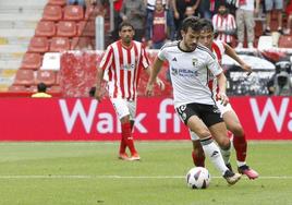 Curro conduce el balón perseguido por el defensor del Sporting.