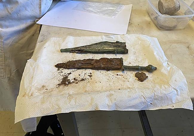 La restauradora está tratando de limpiar tanto la funda del puñal como el arma.