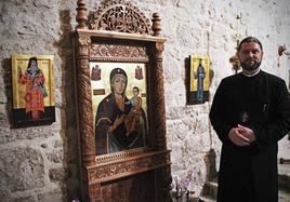 El padre ortodoxo Danut Mures posa frente a algunos iconos que permanecen fijos en la iglesia católica de Villatoro.