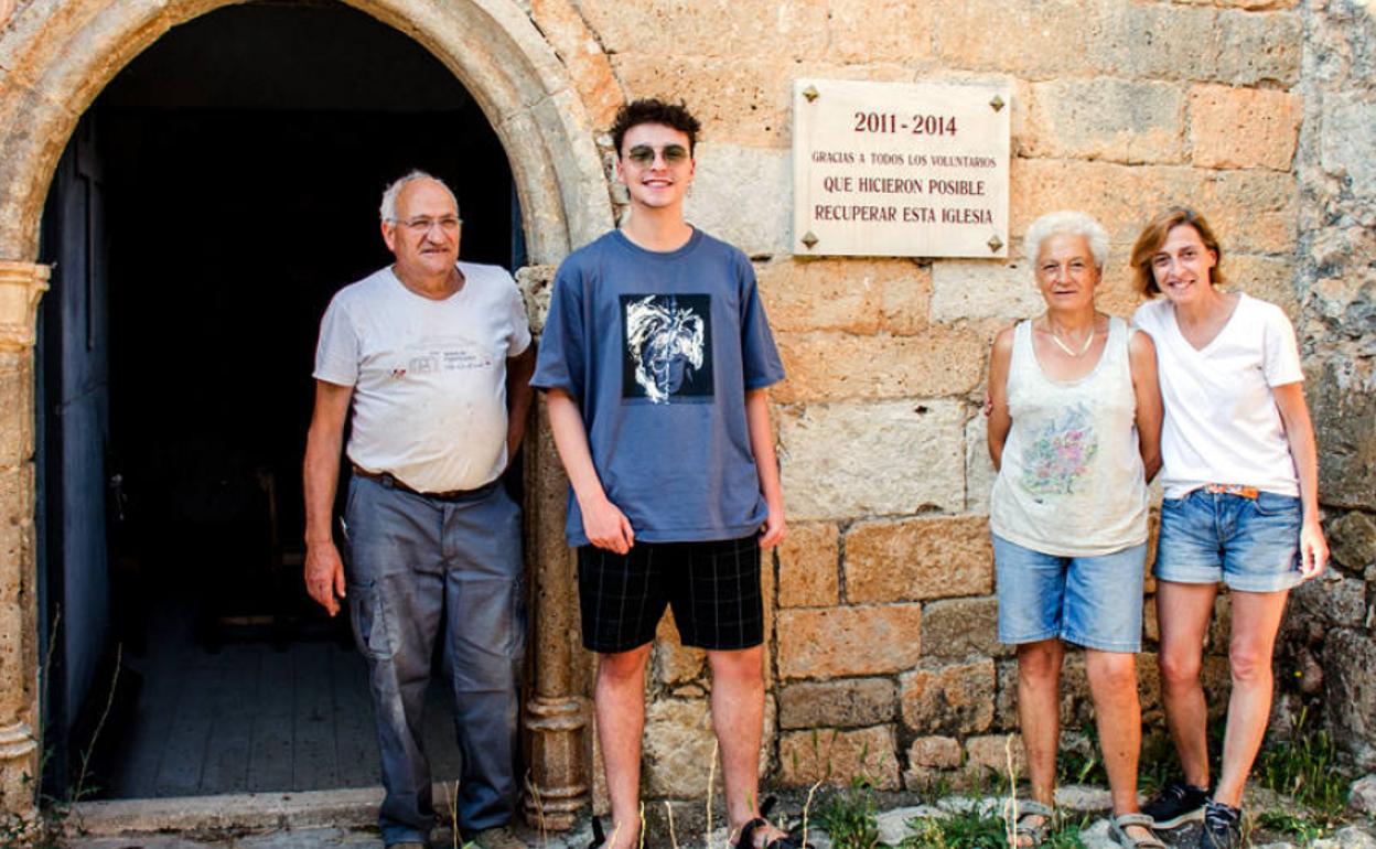 Algunos de los voluntarios, entre ellos José María Ruiz a la izquierda, que hicieron posible la restauración de la iglesia junto a una placa colocada en la entrada al templo. 