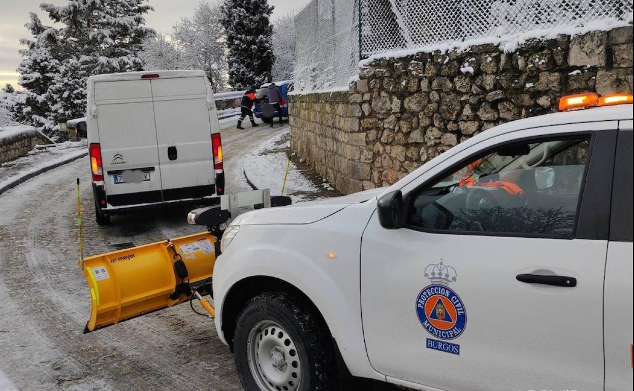 Un quitanieve de Protección Civil despeja la carretera mientras dos personas empujan un coche