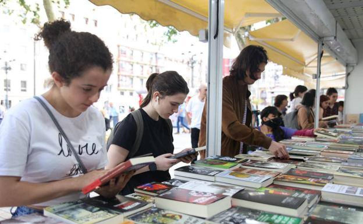 Varios jóvenes observan ejemplares durante una feria del libro