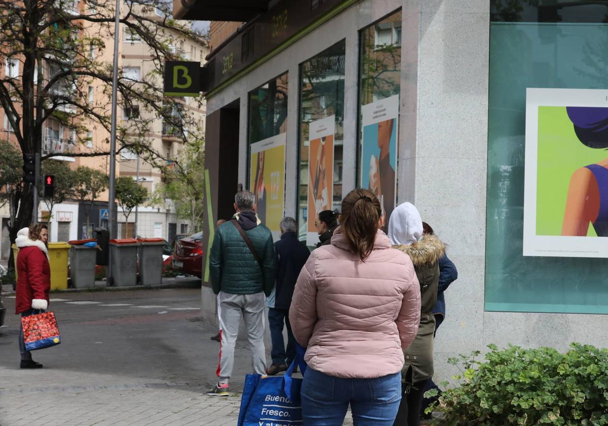 Personas esperando en una oficina bancaria para cobrar la prestación por desempleo.