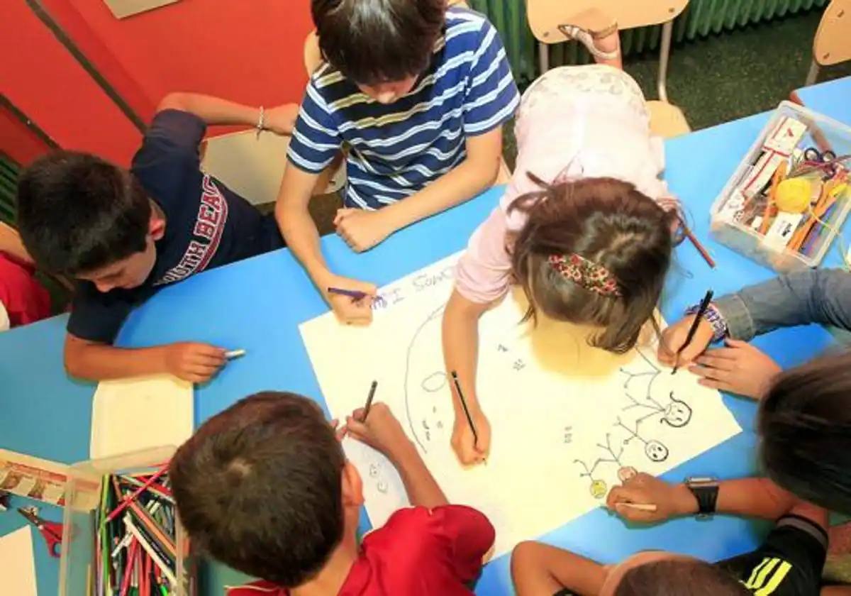 Un grupo de niños pinta en una cartulina.