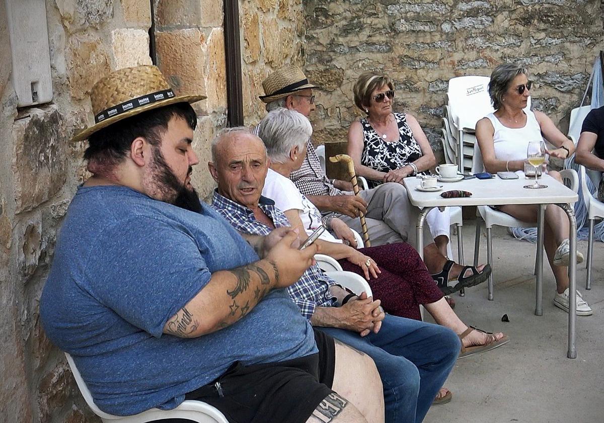 Imagen principal - Adrián con los vecinos en la cantina de Quintanilla de las Viñas. 